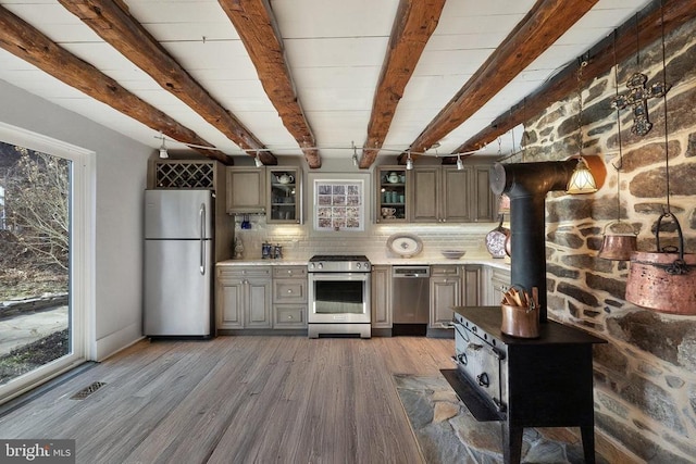 kitchen with appliances with stainless steel finishes, plenty of natural light, dark hardwood / wood-style floors, and beamed ceiling