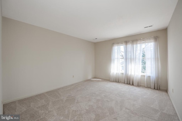 empty room featuring carpet flooring, visible vents, and baseboards