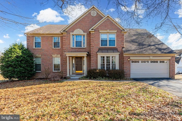 view of front of house with driveway, a garage, roof with shingles, a front lawn, and brick siding