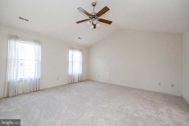 spare room with lofted ceiling, visible vents, a ceiling fan, and light colored carpet