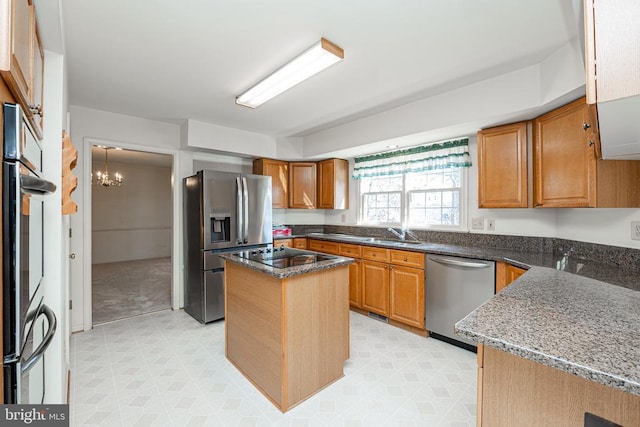 kitchen with appliances with stainless steel finishes, dark stone counters, a kitchen island, and light floors