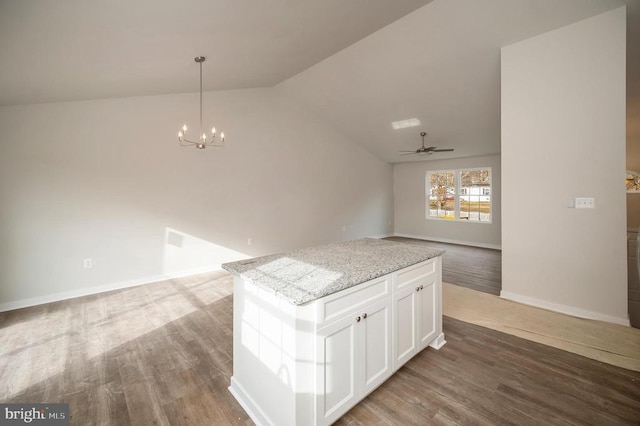 kitchen featuring wood-type flooring, hanging light fixtures, a kitchen island, light stone countertops, and white cabinets