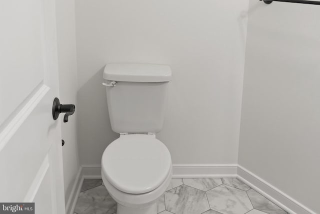 bathroom featuring marble finish floor, baseboards, and toilet