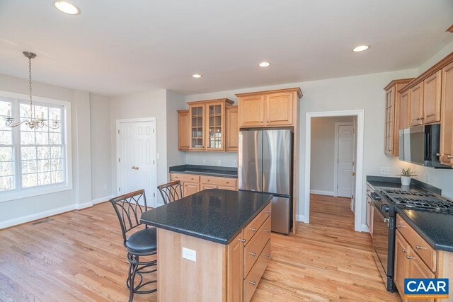 kitchen with dark countertops, appliances with stainless steel finishes, glass insert cabinets, light wood-style floors, and recessed lighting