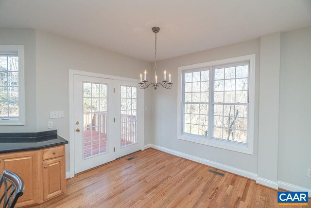 unfurnished dining area featuring a chandelier, light wood finished floors, visible vents, and baseboards