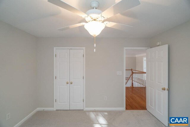 unfurnished bedroom with carpet floors, a closet, ceiling fan, and baseboards