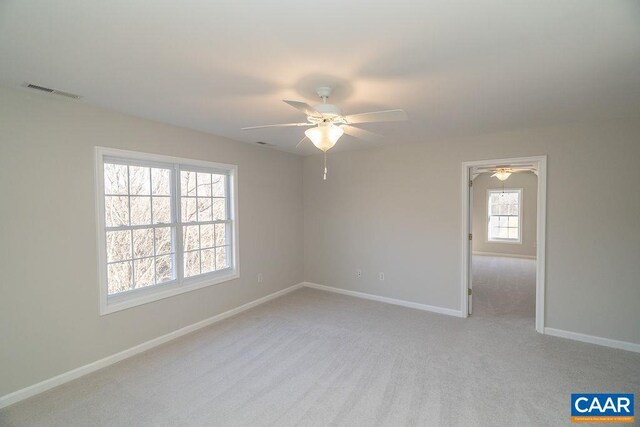 unfurnished room featuring baseboards, a ceiling fan, visible vents, and light colored carpet