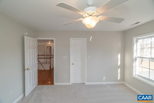 empty room with light carpet, baseboards, visible vents, and a wealth of natural light