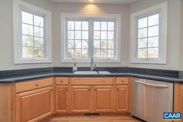 kitchen with a sink, visible vents, stainless steel dishwasher, brown cabinets, and dark countertops