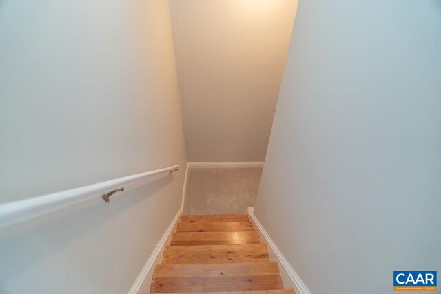 staircase featuring baseboards and wood finished floors