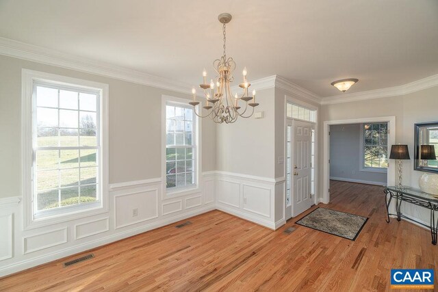 unfurnished dining area featuring light wood-style floors, visible vents, plenty of natural light, and ornamental molding