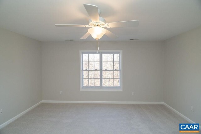 empty room with a ceiling fan, light colored carpet, visible vents, and baseboards