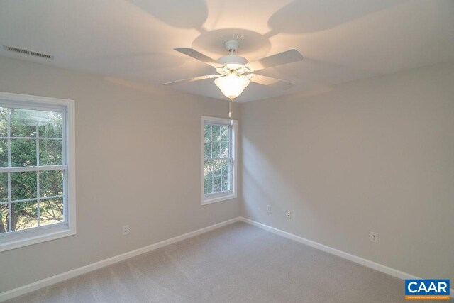 unfurnished room featuring carpet floors, visible vents, baseboards, and a ceiling fan