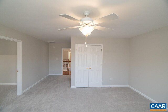 unfurnished bedroom with light carpet, a closet, a ceiling fan, and baseboards