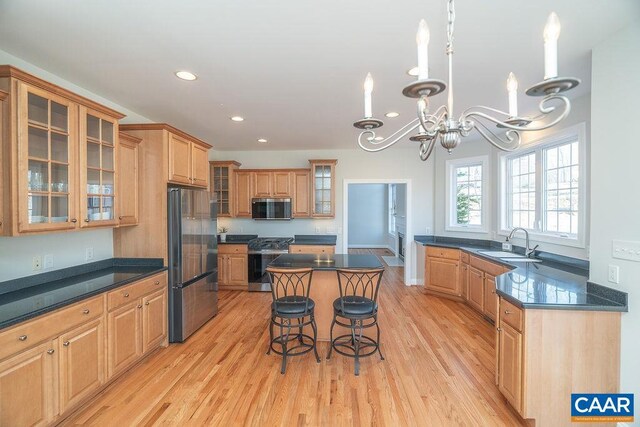 kitchen featuring appliances with stainless steel finishes, light wood-type flooring, a sink, and a breakfast bar