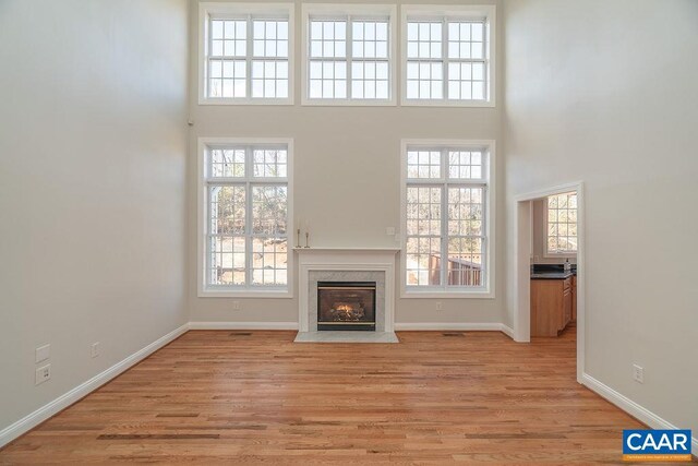 unfurnished living room with a premium fireplace, a wealth of natural light, and light wood-style floors