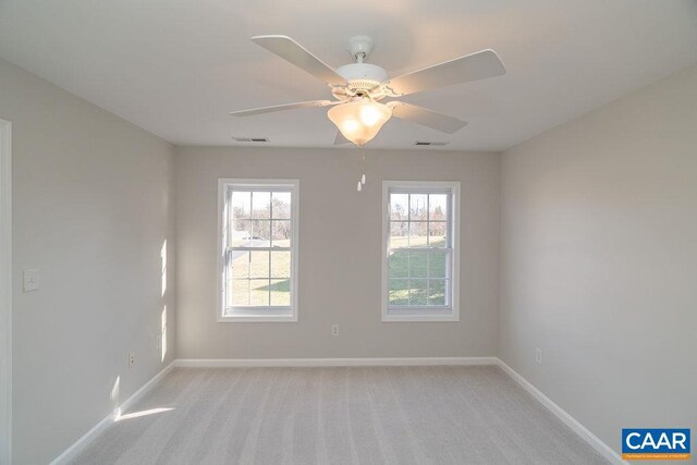 spare room with visible vents, ceiling fan, light carpet, and baseboards