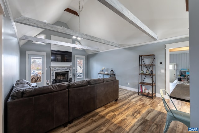 living area featuring lofted ceiling with beams, a fireplace, baseboards, and wood finished floors