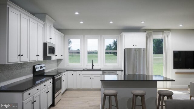 kitchen featuring appliances with stainless steel finishes, a kitchen bar, sink, and white cabinets