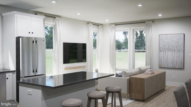 kitchen featuring a kitchen island, stainless steel fridge, white cabinets, and light wood-type flooring