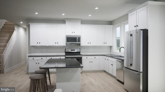 kitchen featuring a kitchen bar, sink, a kitchen island, stainless steel appliances, and white cabinets