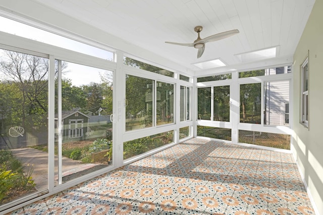 unfurnished sunroom with ceiling fan and a skylight