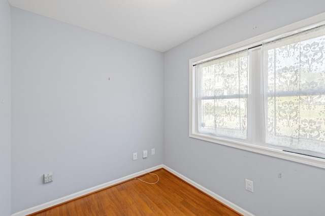 spare room with baseboards and wood finished floors