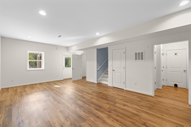unfurnished living room with recessed lighting, baseboards, light wood-type flooring, visible vents, and stairway
