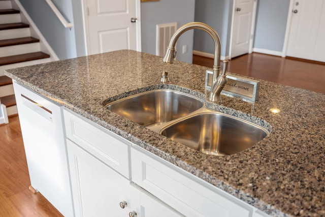 interior details with visible vents, a sink, dark stone counters, and white cabinets
