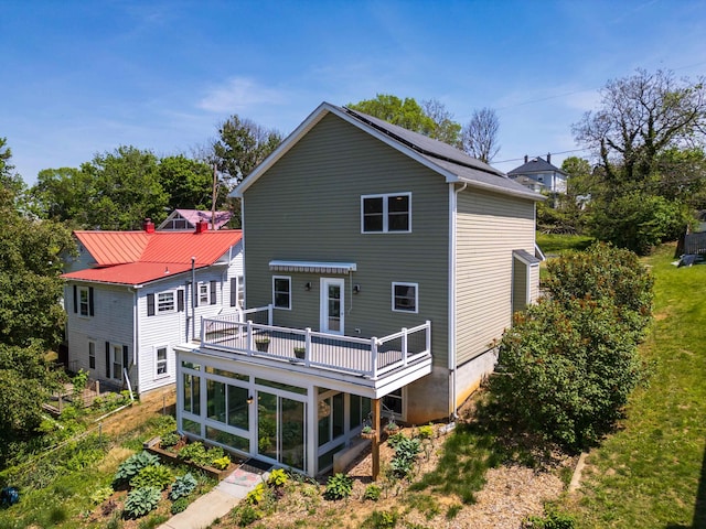 rear view of property featuring a sunroom and a wooden deck