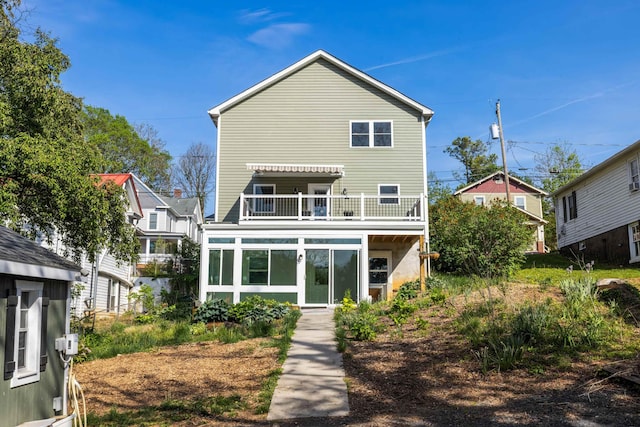 rear view of house featuring a sunroom and a balcony