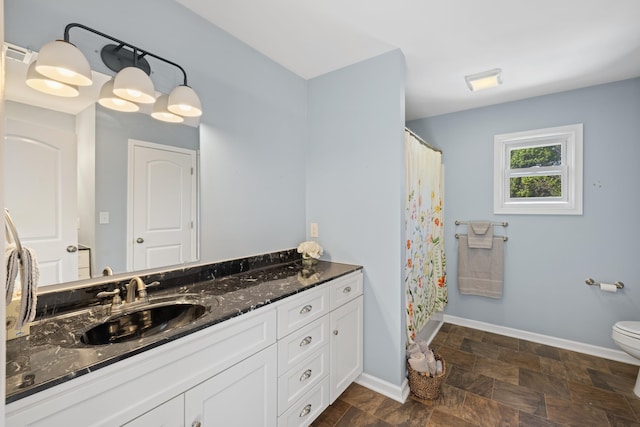 full bath featuring vanity, stone finish flooring, baseboards, and toilet