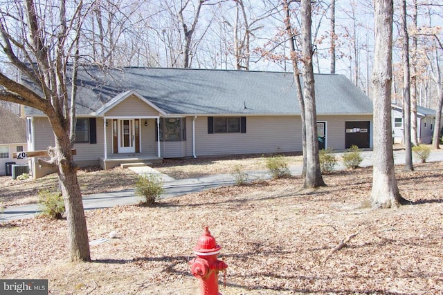 ranch-style home featuring covered porch, central AC, and a shingled roof