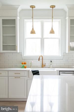 kitchen with hanging light fixtures, tasteful backsplash, sink, and white cabinets