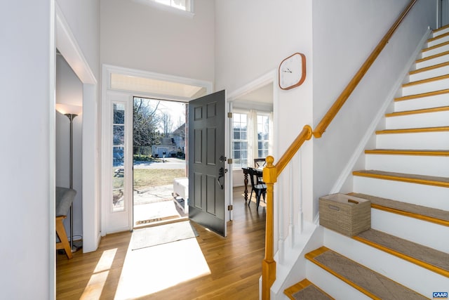 foyer entrance featuring a high ceiling, wood finished floors, and stairs