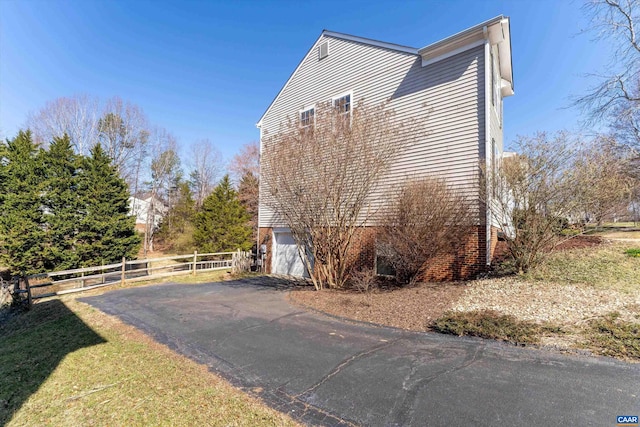 view of property exterior with fence, a garage, and driveway