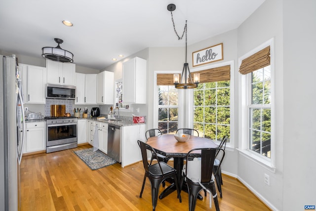 kitchen featuring light wood-type flooring, a sink, light stone counters, white cabinetry, and appliances with stainless steel finishes