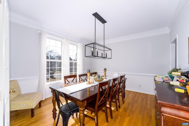 dining area featuring a chandelier, ornamental molding, and wood finished floors