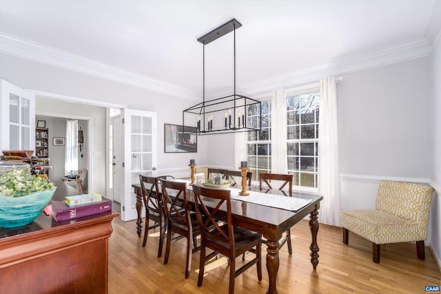 dining room featuring an inviting chandelier, crown molding, and light wood-style floors