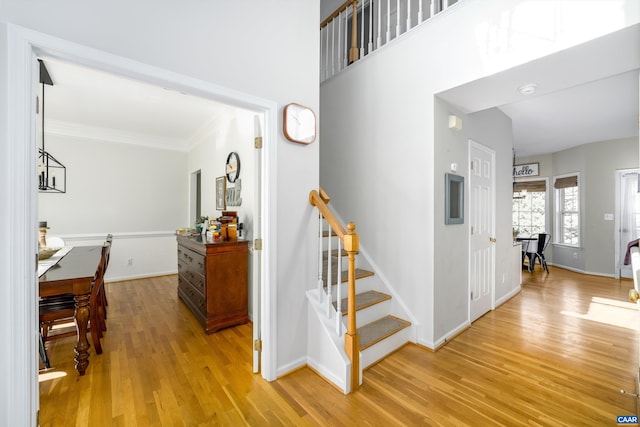 staircase featuring wood finished floors, baseboards, and ornamental molding