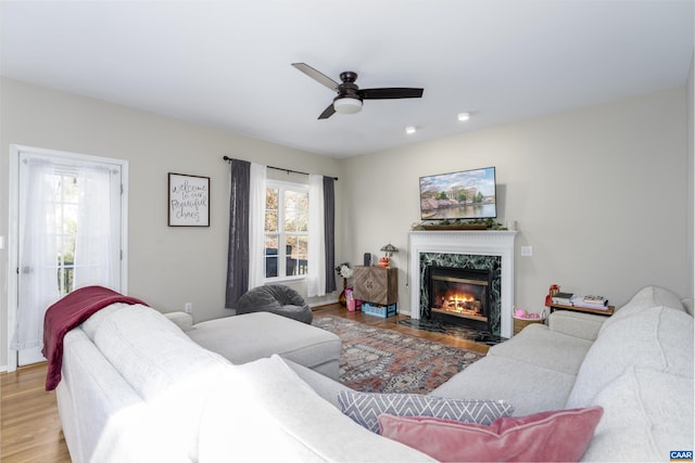 living area featuring a high end fireplace, recessed lighting, ceiling fan, and wood finished floors