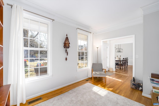 sitting room featuring a wealth of natural light, visible vents, and crown molding