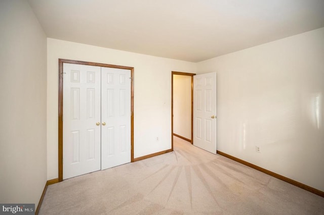 unfurnished bedroom with light carpet, baseboards, and a closet