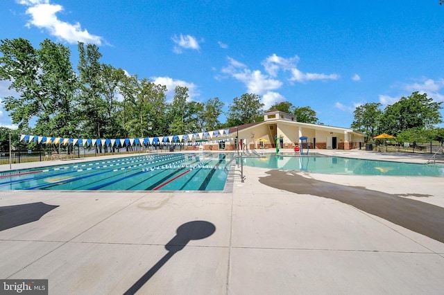 pool with a patio area and fence