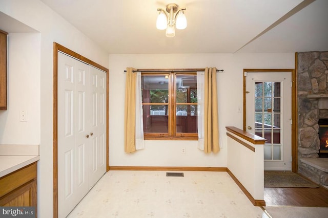 entryway featuring visible vents, a stone fireplace, and baseboards