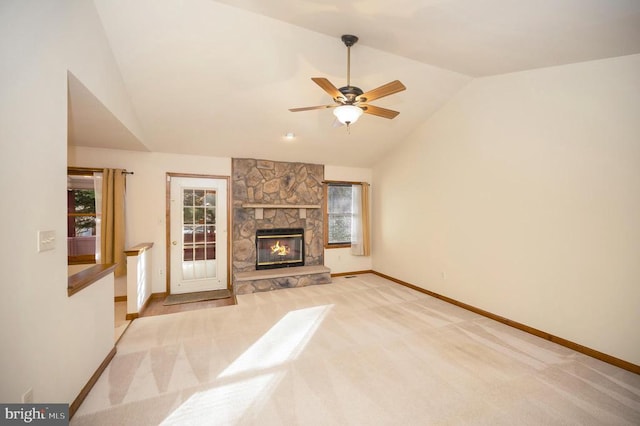 living area featuring light carpet, a stone fireplace, vaulted ceiling, and baseboards