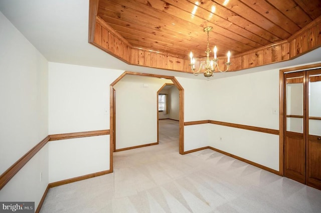 empty room featuring wood ceiling, baseboards, and light colored carpet