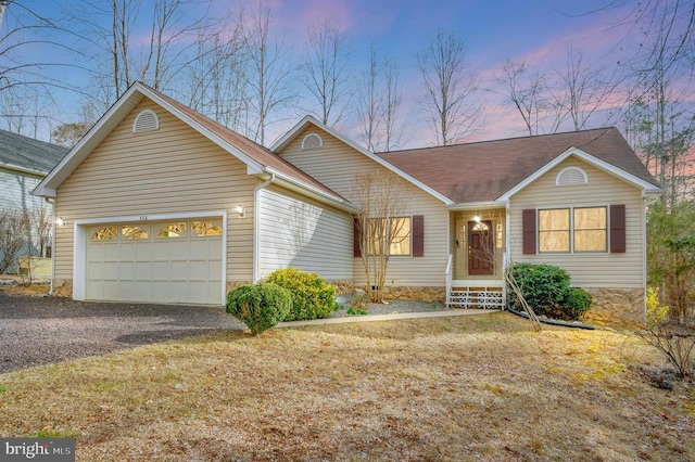 ranch-style house featuring gravel driveway and an attached garage