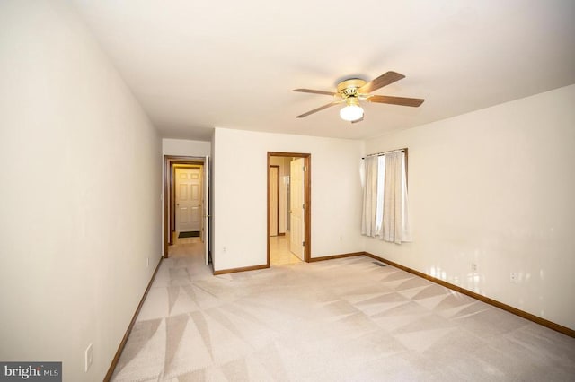 unfurnished bedroom with light carpet, connected bathroom, a ceiling fan, and baseboards