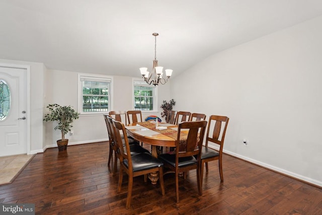 dining space featuring lofted ceiling, hardwood / wood-style floors, a chandelier, and baseboards